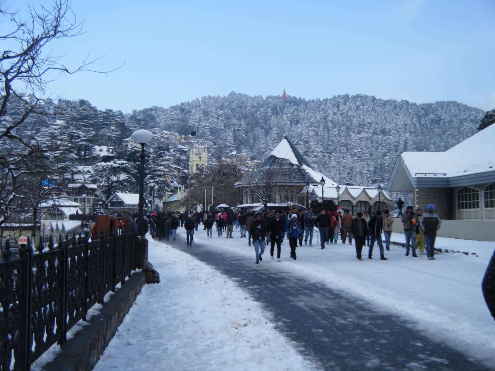 The Ridge in Shimla under fresh snow, with visitors walking past the library